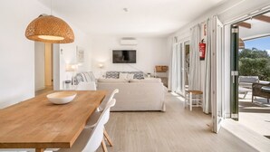 Una sala de estar moderna con una mesa de comedor de madera, un sofá blanco y un televisor montado en la pared.
