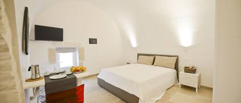A bedroom with a bed, bedside table, and a desk with a chair.