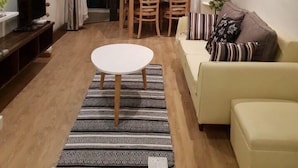 Un salon moderne comprenant un coin repas, un canapé, un téléviseur et un lustre.