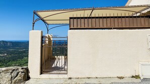 Un balcón con una reja de metal, una pared blanca y vistas al paisaje.