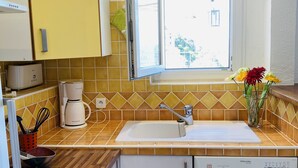 Una cocina con ventana, cafetera, lavavajillas y estufa.