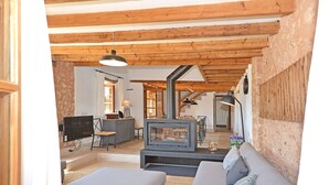 A cozy living room with a fireplace, a sofa, a television, and a dining area. - Can Cortana - Charming country house with pool in Inca, Mallorca (Inca)