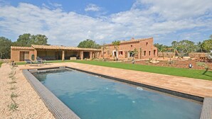A pool with a tiled deck, a covered patio area, and a brick building with a flat roof. - Can Cortana - Charming country house with pool in Inca, Mallorca (Inca)