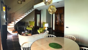 Un vaste espace de vie comprenant un escalier, une table à manger ronde et des meubles modernes.