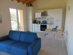 Una sala de estar con un sofá azul y una zona de comedor con una mesa preparada para dos.