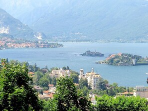 Un pueblo a orillas del lago con edificios históricos y una iglesia destacada, rodeado de montañas y vegetación.