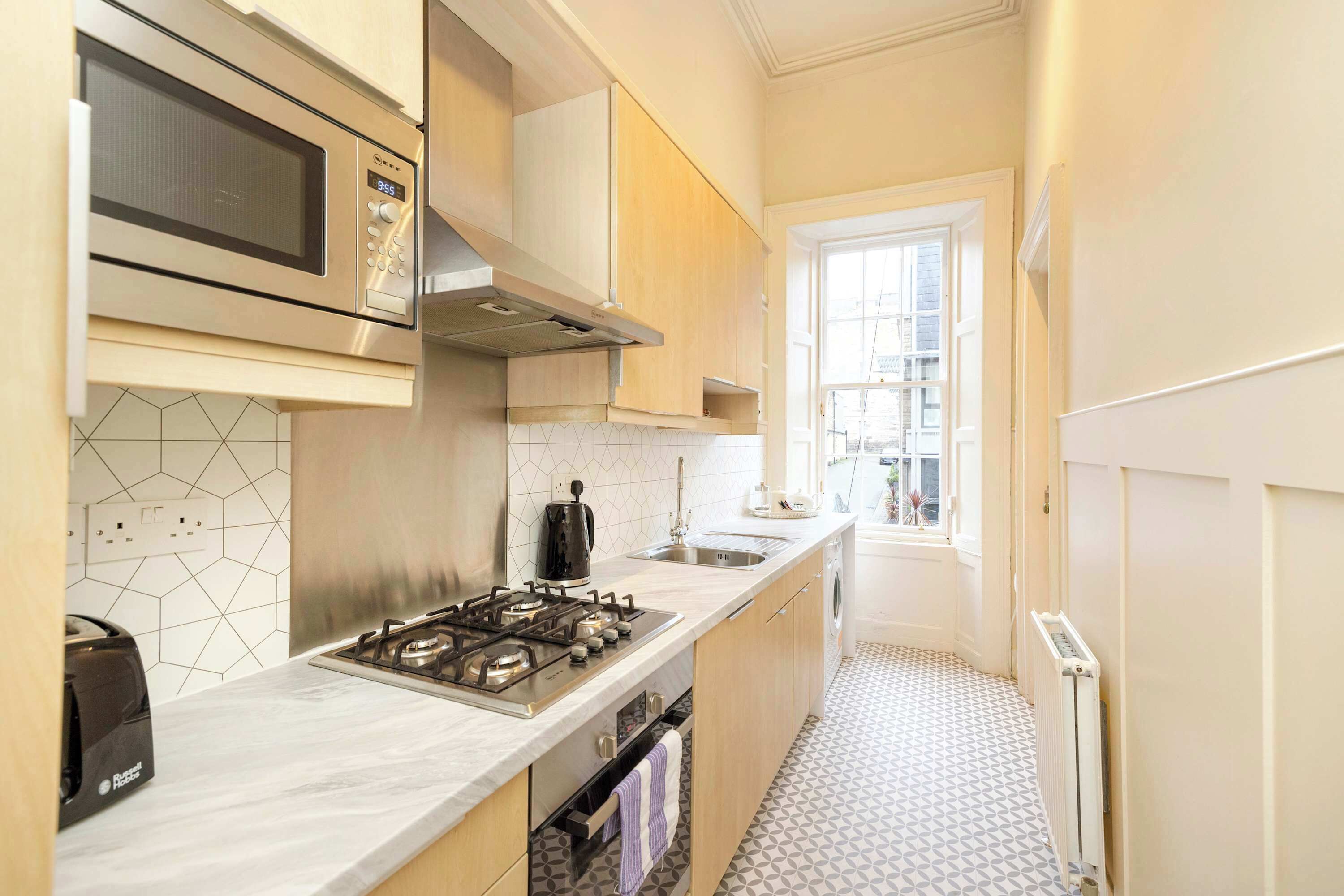 A compact kitchen with a microwave, stove, and sink.