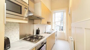 Una cocina compacta con microondas, estufa y lavamanos.