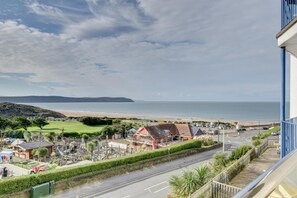 A coastal view with a road, buildings, and a beach.