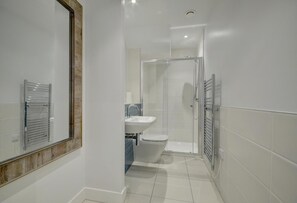 Un bagno moderno con cabina doccia in vetro, un water e un lavandino.