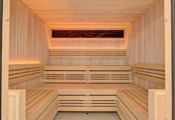 A sauna with wooden benches and a central heating element.