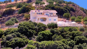 A two-story house with a red-tiled roof, surrounded by dense greenery and hills. - Luxurious Private Villa with Private Pool and Sea Views- 6 min drive from beach (gouves)