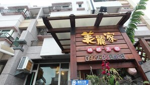 A hotel entrance with a wooden signboard displaying the name and contact number. - Beauty Home Homestay (Hualien City)
