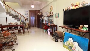 A living room with a staircase, a dining table, a sofa, a TV, and a painting. - Beauty Home Homestay (Hualien City)