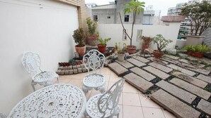 A rooftop patio with white metal furniture, potted plants, and a tiled floor. - Beauty Home Homestay (Hualien City)