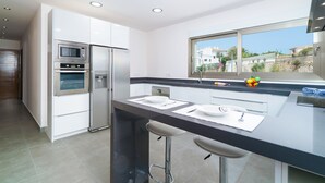 Una cocina moderna con electrodomésticos integrados, un amplio ventanal y una barra.