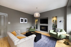 Una sala de estar moderna con sofá, sillones, una mesa de centro, chimenea y televisor.