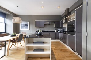 Uma cozinha moderna com armários escuros, uma ilha central e um espaço de refeições com mesa e cadeiras.