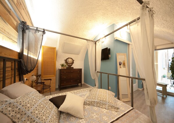 Ein Schlafzimmer mit Bett, Kommode, Spiegel und Fernseher.