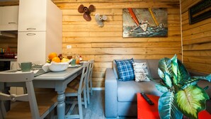 Un rincón acogedor con pared de madera, una mesa de comedor con sillas, un sofá con cojines y un cuadro de un barco.