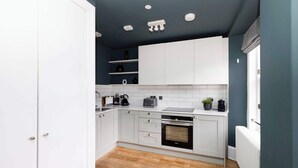Une cuisine avec des meubles blancs, un four noir et un plancher en bois.