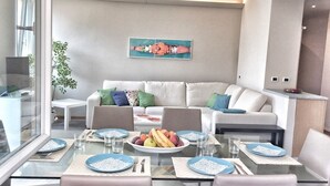 Un comedor moderno con una mesa de vidrio, un sofá blanco y un cuadro en la pared.