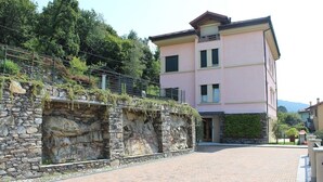 Un edificio rosa con un muro de piedra y un área pavimentada en su frente.
