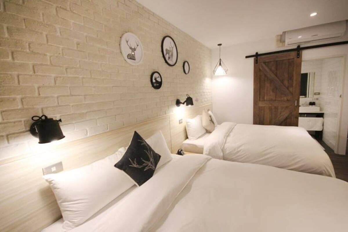 Habitación de hotel con dos camas, una pared de ladrillo y una puerta corrediza estilo granero.