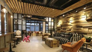 A modern interior with a wooden ceiling, striped sofa, and a pink chair. - Pinestone Inn (Ji'an)