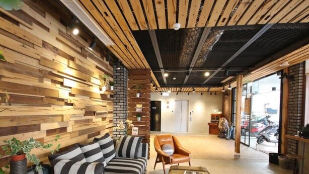 A modern interior with a wooden wall, a striped sofa, a leather armchair, and a vintage suitcase. - Pinestone Inn (Ji'an)