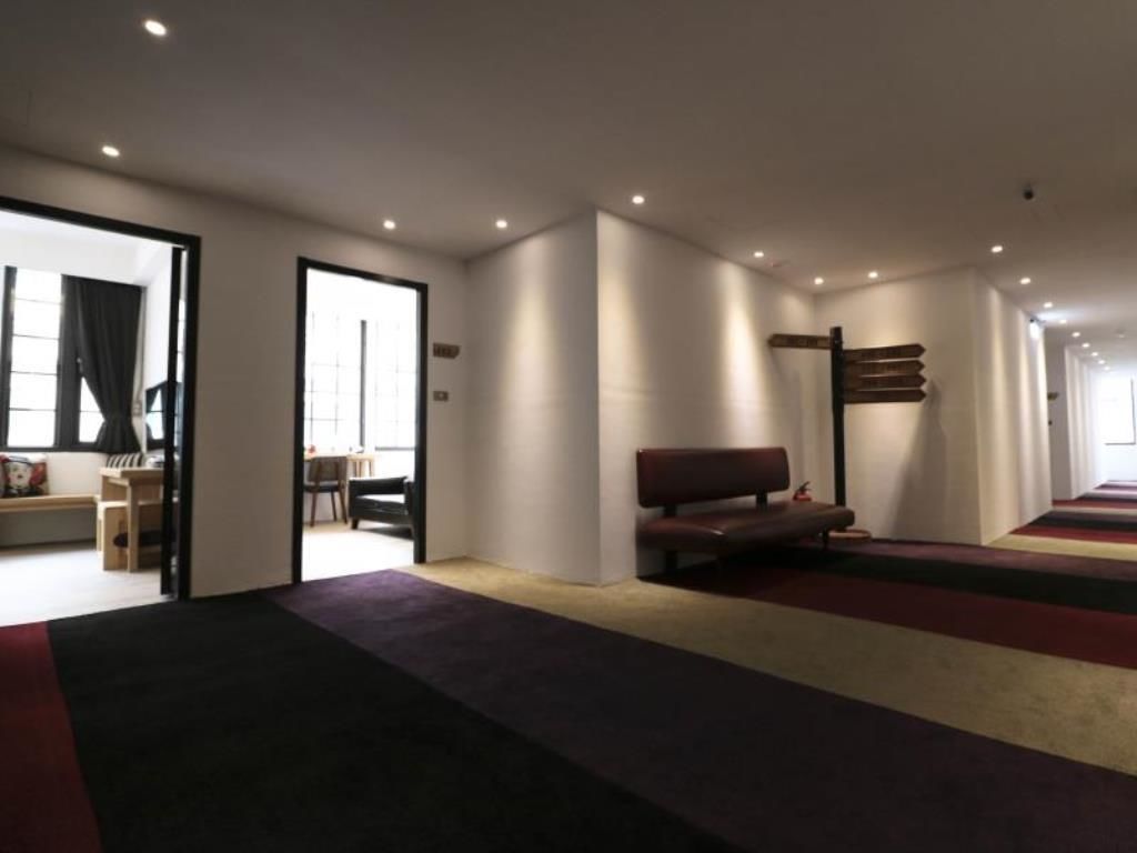 A modern interior with a bench, a door leading to another room, and a patterned carpet.