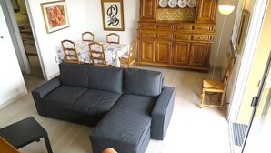 A living room with a dark-colored sofa, a small table, and a cabinet with decorative plates. - Selva 1 lake view apartment in Ghiffa with pool (Ghiffa)