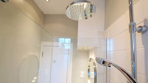 Un baño moderno con cabina de ducha de vidrio, cabezal de ducha de mano y grifo empotrado.