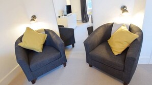 Una habitación con dos sillones, una mesita y un aparador blanco.