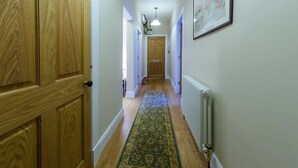 A hallway with wooden doors, a patterned rug, and a radiator. - Trendy & Stylish Apartment in Edinburgh's New Town (Edinburgh)