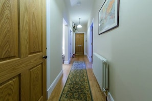 Un couloir avec des portes en bois, un tapis à motifs et un radiateur.