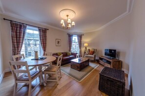 A living room with a round table, sofa, and television. - Trendy & Stylish Apartment in Edinburgh's New Town (Edinburgh)