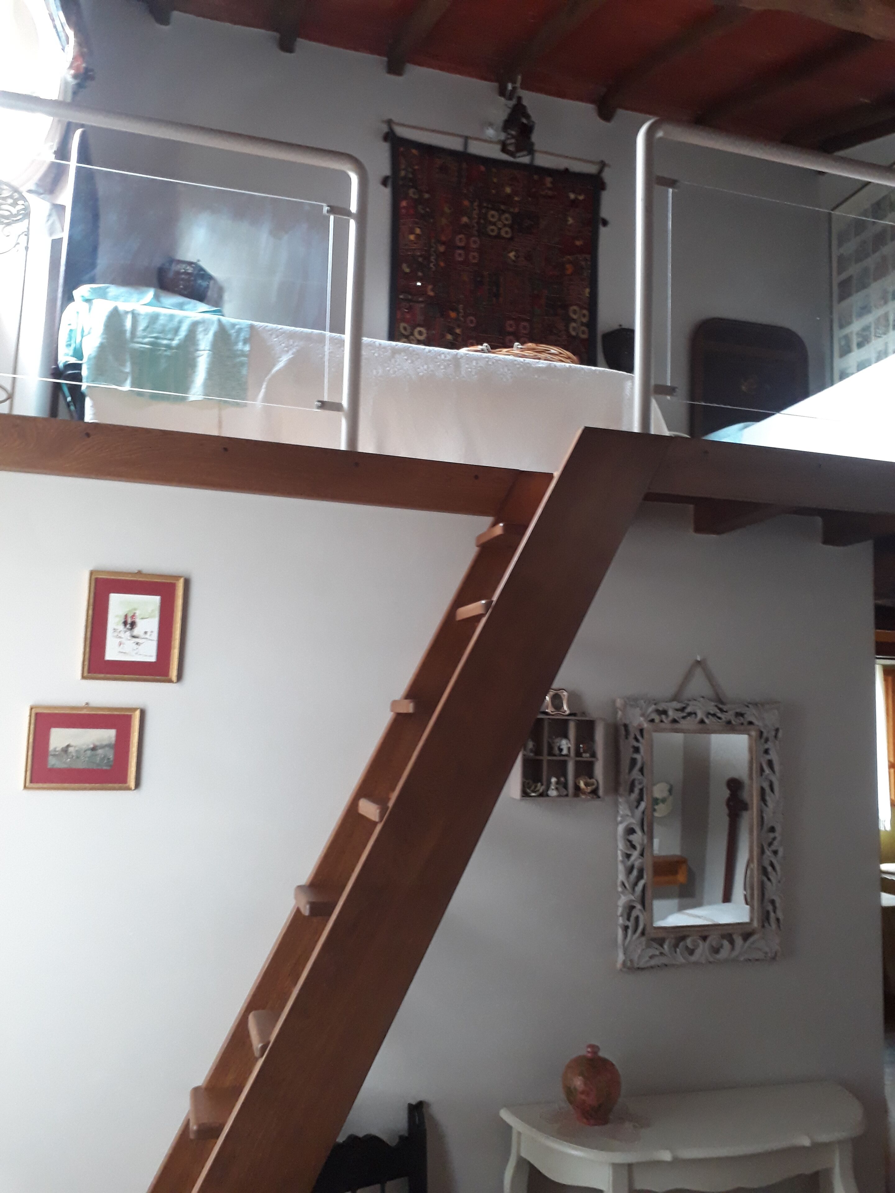A room with a bunk bed, a small table, a mirror, and two framed pictures on the wall.