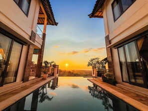 A modern hotel with a pool reflecting the sunset.