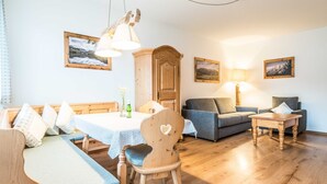 Ein gemütliches Wohnzimmer mit einem Holzespeisetisch, einer Couch, einem Sessel und einer Lampe.