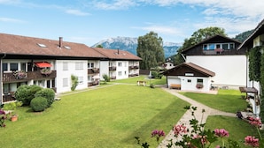 Ein Innenhof mit Rasenfläche, Bänken und einem kleinen Gebäude mit Balkon.