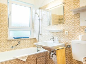 A bathroom with a bathtub, sink, and toilet. There is a window above the bathtub and a mirror above the sink. - E4 Classic apartment***, 53sqm, balcony, suitable for allergy sufferers (Oberaudorf)
