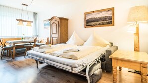 Ein Zimmer mit einem Bett, einem Holztisch, einer Bank und einer Lampe.