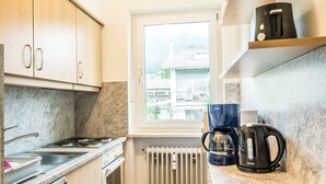 Eine kleine Küche mit Gaskochfeld, Backofen und Kaffeemaschine auf der Arbeitsfläche.