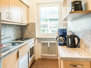 Eine kleine Küche mit Gaskochfeld, Backofen und Kaffeemaschine auf der Arbeitsfläche.