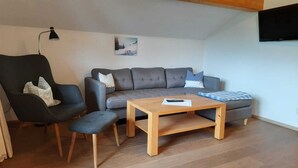 A modern living room with a grey sofa, a wooden coffee table, and a black armchair.