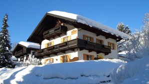 A multi-story chalet with wooden balconies and snow-covered surroundings.