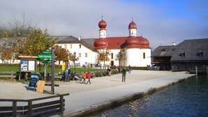 A building with a red dome and white walls, a dock, and a calm water body.
