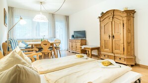Una habitación de hotel con cama, escritorio, televisor y armario de madera.