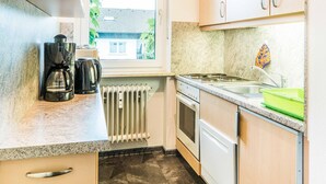 Una cocina compacta con ventana, cafetera, estufa y pileta.